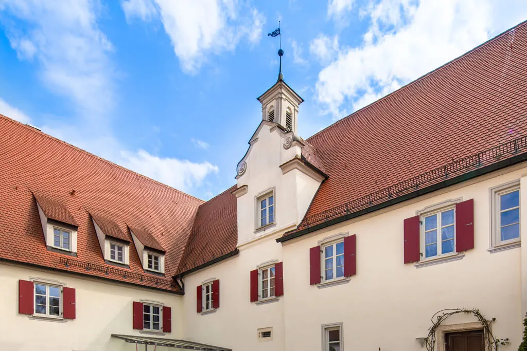 Weiße Schlossfassade mit Kapelle und roten Fensterläden